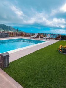 a swimming pool with chairs and the ocean in the background at Sea House in Povoação