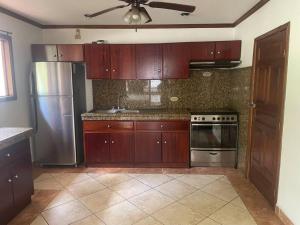 a kitchen with wooden cabinets and a stainless steel refrigerator at Comparte con la Naturaleza in Escazu