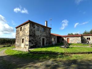 una vieja casa de piedra en un campo de hierba en As Casiñas Bed & Breakfast Porto de Bois, en Lugo