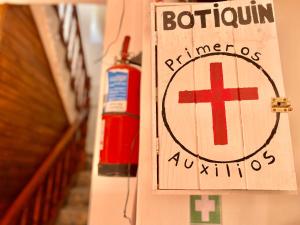 a sign on a wall with a red cross and a fire extinguisher at Hospedaje La Merced Humahuaca in Humahuaca