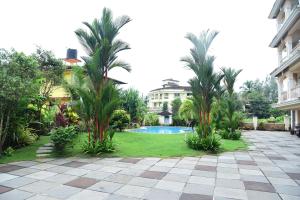 a courtyard with palm trees and a swimming pool at Zalor Residency 2 in Varca