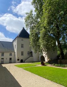 un grand bâtiment blanc avec un arbre et de l'herbe dans l'établissement Charmantes Chateau Lichter - Burghaus, à Ließem