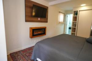 a bedroom with a bed and a tv on the wall at Pousada Orquidea da Serra in Petrópolis