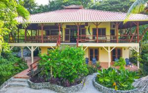 a yellow house with a porch and some bushes at Bluff Beach Retreat in Bocas Town