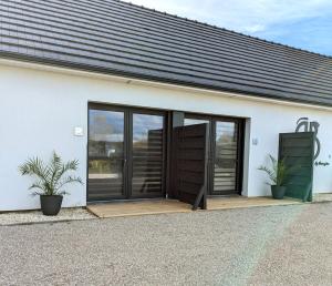 a white building with sliding glass doors and two plants at Jardin Secret in Groffliers