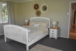 a bedroom with a white bed and a mirror on the wall at Beautiful home with short stroll to Havelock Village in Havelock North