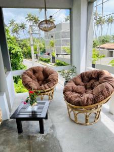 two chairs and a coffee table on a porch at Cocoplant Surf Inn in Midigama