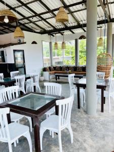 a dining room with white chairs and tables and windows at Cocoplant Surf Inn in Midigama