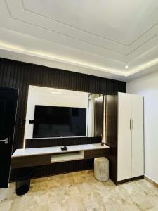 Una sala de estar con un televisor grande y un mueble blanco. en Tastic Homes ng, en Port Harcourt