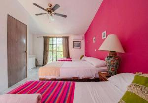 een roze slaapkamer met 2 bedden en een plafondventilator bij Villa México a 5 Minutos de la playa in Cancun