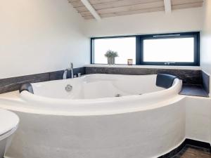 a large white bath tub in a bathroom with a toilet at 5 star holiday home in Hirtshals-By Traum in Hirtshals +26 photos