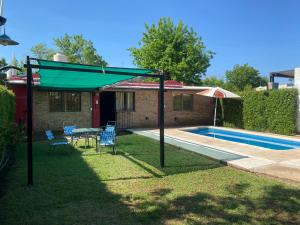 eine Terrasse mit einem Tisch und einem Sonnenschirm neben einem Pool in der Unterkunft CASA RINCON DE VISTALBA in Vistalba