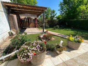 ein Garten mit Blumen in Fässern und einem Holztor in der Unterkunft CASA RINCON DE VISTALBA in Vistalba