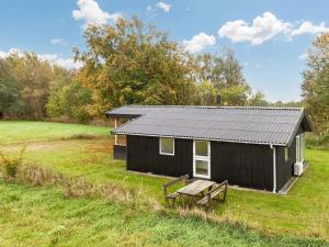 a black cabin with a picnic bench in a field at 5 person holiday home in Læsø in Læsø +28 photos