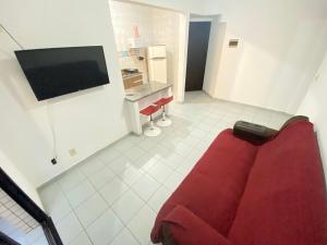 a living room with a red couch and a tv at Pé na areia praia da Guilhermina III in Praia Grande