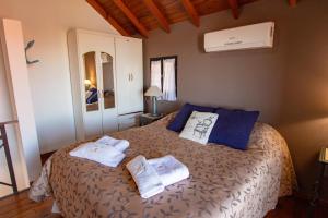 a bedroom with a bed with towels on it at Cabañas Dalga Inn in Merlo