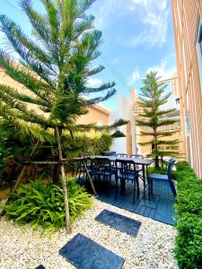 un patio avec tables et chaises et un palmier dans l'établissement Gaia Pool Villa Pattaya, à Nong Prue