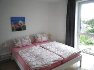 a bedroom with a pink bed with a window at Kniepsand in the Amrumer Welle in Wittdün