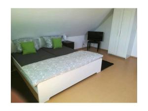 a bedroom with a bed with green pillows and a television at Tromm - Blick Comfortable holiday residence in Rimbach