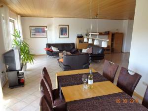 a living room with a table and chairs and a television at Marmann - large holiday apartment in Osann-Monzel