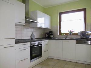 a kitchen with white cabinets and a window at Marmann - large holiday apartment in Osann-Monzel +6 photos