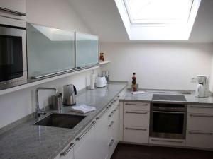 Una cocina con gabinetes blancos y un fregadero y una ventana. en Havelpalais Comfortable holiday residence, en Potsdam