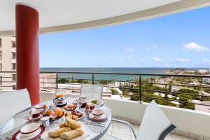 Ramada Hotel & Suites by Wyndham Noumea في نومْيا: طاولة طعام على شرفة مطلة على المحيط