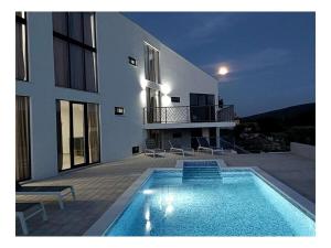 a house with a swimming pool in front of a building at Bagulina Comfortable holiday residence in Drniš