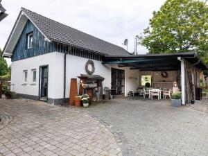 a white house with a black roof and a patio at LebensArt in the old horse stable in Erndtebrück