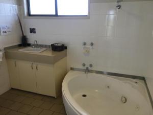 a bathroom with a sink and a bathtub at Capricorn Motor Inn in Mulwala