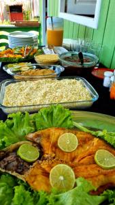 a table full of food with fish and lettuce at POUSADA DA DRI LODGE in Aiparuça