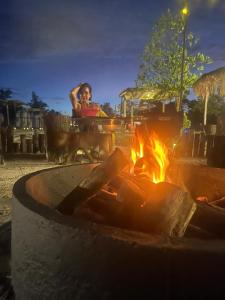 une femme assise à une table près d'un feu dans l'établissement Mai Rut Beach Eco Resort and Camping, à Ban Nong Wiwat