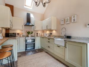 una grande cucina con armadi bianchi e lampadario a braccio di The Old Moat Barn a Elton