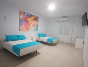 a bedroom with two beds and a painting on the wall at Hostal El Encuentro in Olula del Río