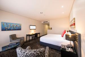 a bedroom with a bed, chair, desk and a television at The Colmslie Hotel in Brisbane