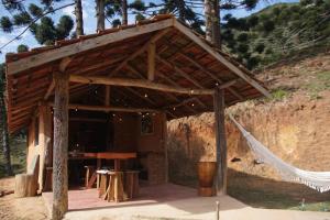 a wooden pavilion with a table and a hammock at Casa das Olivas in São Bento do Sapucaí