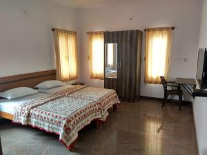 a bedroom with a bed and a desk and windows at Aashraya Home Stay in Mysore