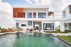 a villa with a swimming pool in front of a house at Kamalie Bali Villa 4 élégant rooms, rice Fields ,Ocean , Pool, jacuzzi, Rooftop and Staff to take care of you in Tanah Lot