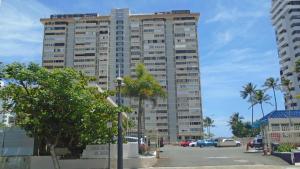 a tall building with palm trees in a parking lot at Chefs Delight in San Juan