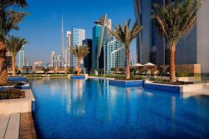 a large swimming pool with palm trees and buildings at JW Marriott Marquis Hotel Dubai in Dubai