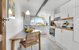 a kitchen with white cabinets and a table and chairs at 3 Bedroom Awesome Home In Løkken in Løkken