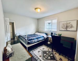 Un dormitorio con una cama y un escritorio y una ventana. en Vancouver Airport 3km away Cozy room Richmond near YVR, en Richmond