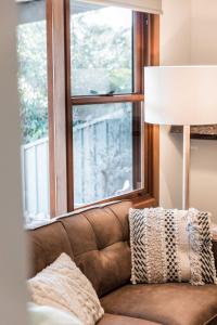eine braune Couch vor einem Fenster in der Unterkunft Porepunkah Cottage in Porepunkah