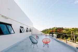 Un balcón con sillas y mesas en un edificio en Spice Motel Okinawa, en Kitanakagusuku