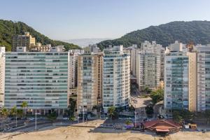 a city with tall buildings in front of a mountain at Apartamento pe na areia nas pitangueiras in Guarujá