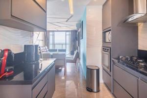 a kitchen with a counter and a living room at Apartamento pe na areia nas pitangueiras in Guarujá