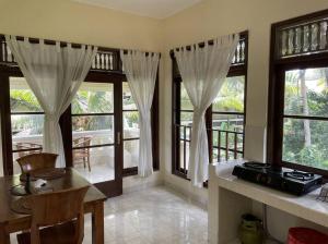 a living room with windows and a table and chairs at Desaka Bisma Ubud in Ubud