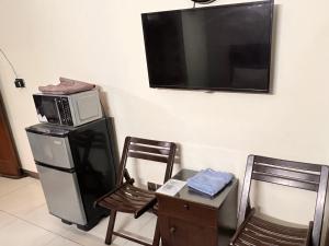 ラーワルピンディーにあるCrescent Cozy Apartmentの壁にテレビがあり、電子レンジと椅子が2脚ある