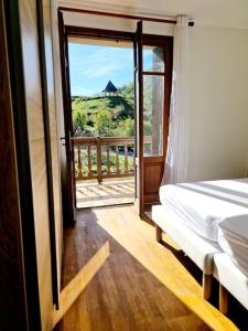 a bedroom with a bed and a door to a balcony at Maison Vidal, au pied de l'Aubrac in Coubisou