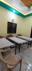 three beds in a room with a chair and a clock at Mallikarjun Residency with AC in Akalkot
